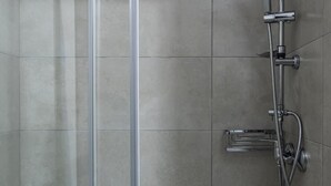 A modern shower enclosure with a glass door, a handheld showerhead, a fixed showerhead, and a handheld shower hose. - Stagiates Guest House Room 3 (Volos)