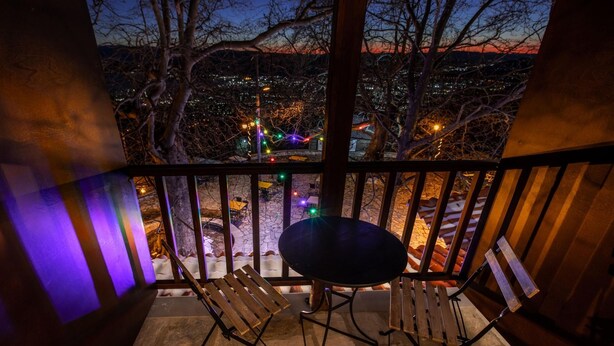 A balcony with a table and two chairs, overlooking a cityscape at dusk. - Stagiates Guest House Room 3 (Volos)