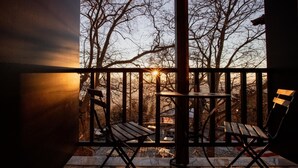 A balcony with two wooden chairs and a table, overlooking a snowy landscape with bare trees and a building in the background. - Stagiates Guest House Room 3 (Volos)