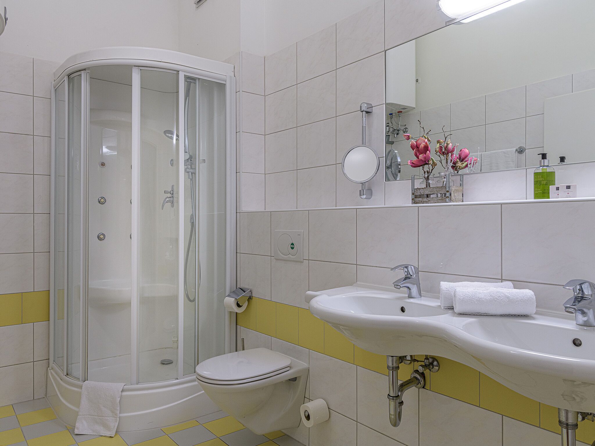 Un baño con cabina de ducha, inodoro y dos lavamanos.