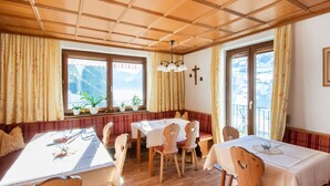 A dining area with wooden tables and chairs, a bench, and large windows with curtains. - Chalet in Hainzenberg Near Ski Slopes (Hainzenberg)