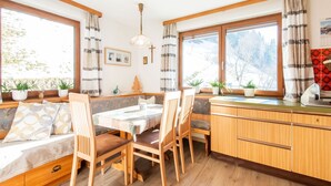 A cozy room with a wooden bench, a dining table, and chairs. There are potted plants on the windowsill, a cross on the wall, and a framed picture. - Chalet in Hainzenberg Near Ski Slopes (Hainzenberg)