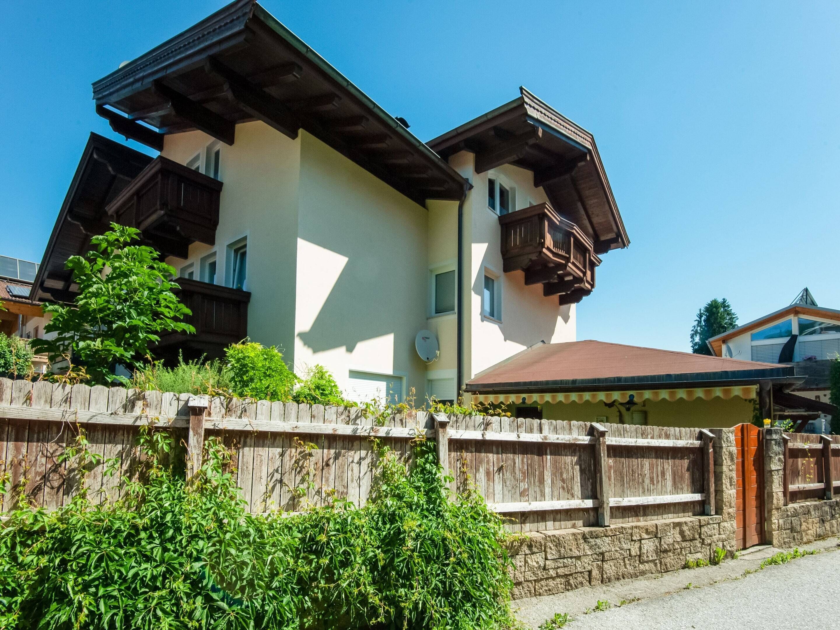 A two-story building with a sloped roof, wooden balconies, and a stone wall in front.