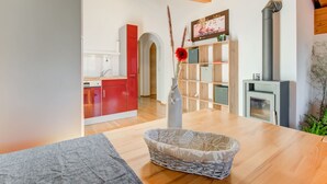 A modern kitchen with red cabinets, a wooden dining table, and a vase with dried plants. - Cosy Flat in Westendorf in Tyrol (Westendorf)