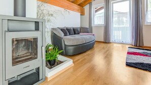 A modern living room with a fireplace, a grey sofa, and a wooden ceiling. - Cosy Flat in Westendorf in Tyrol (Westendorf)
