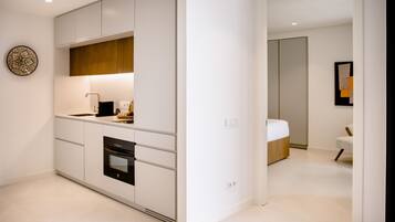 Una cocina moderna con armarios blancos, horno integrado y una encimera con cafetera.