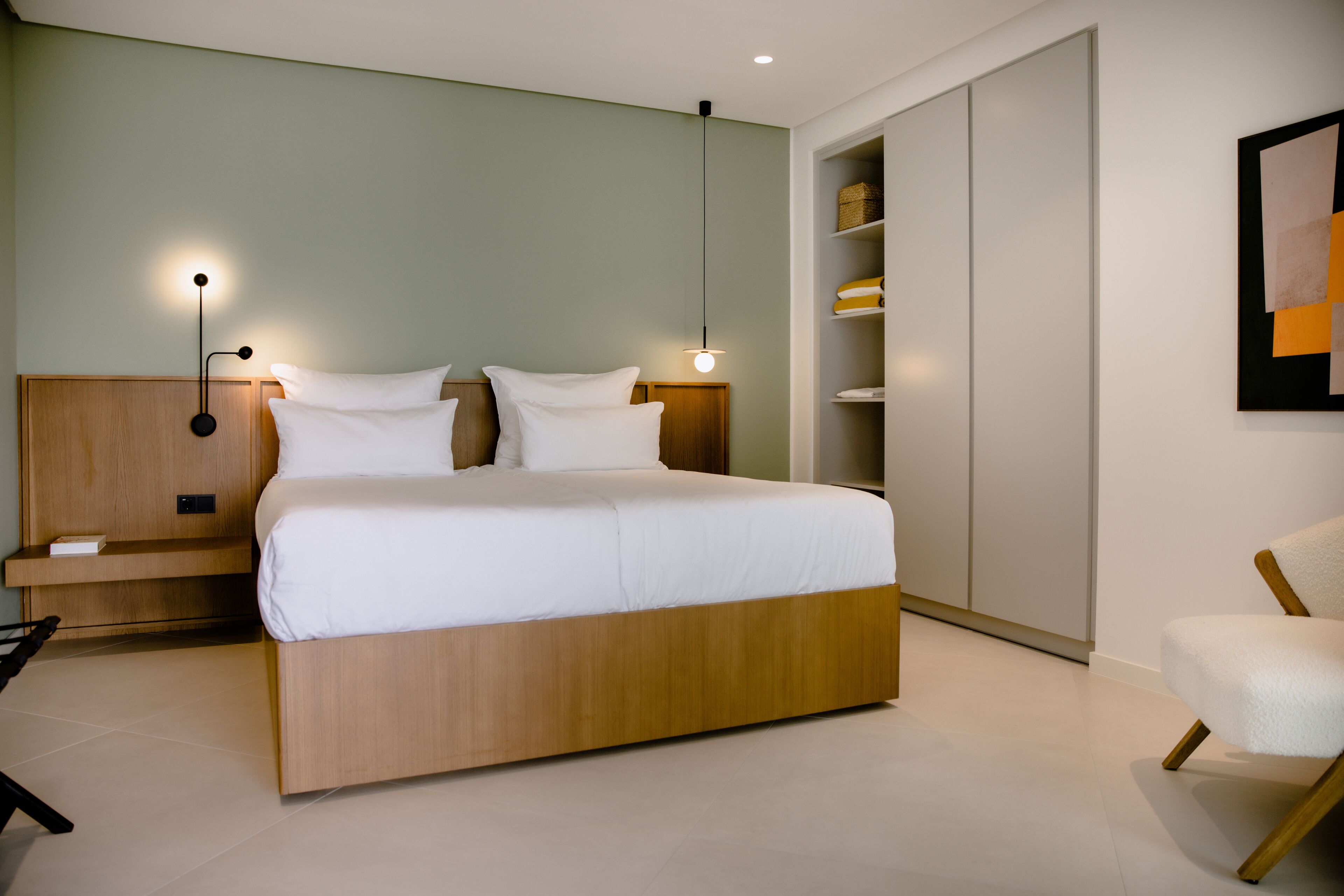Un dormitorio moderno con una cama de madera, mesitas de noche, un armario y una silla.
