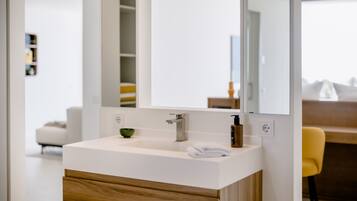 A modern bathroom with a white sink, wooden cabinet, and a large mirror.