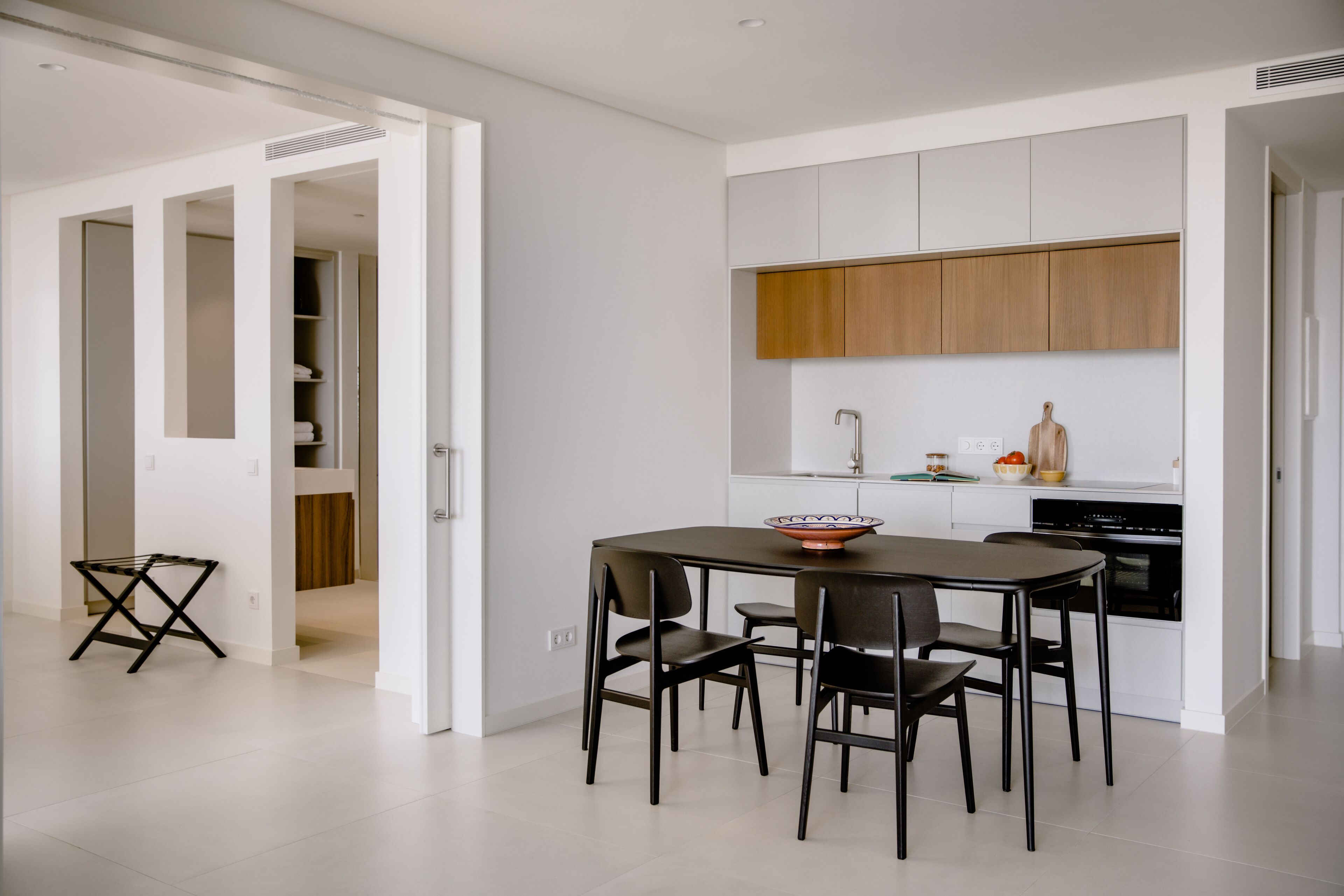 A modern kitchen with white cabinets, a wooden countertop, and a dining area with a table and chairs.