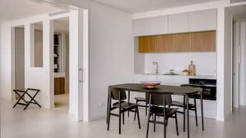Una cocina moderna con armarios blancos, encimera de madera y un comedor con mesa y sillas.