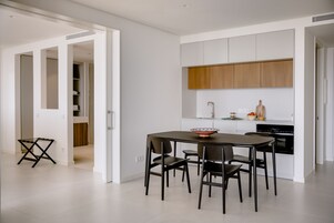 Una cocina moderna con armarios blancos, encimera de madera y un comedor con mesa y sillas.