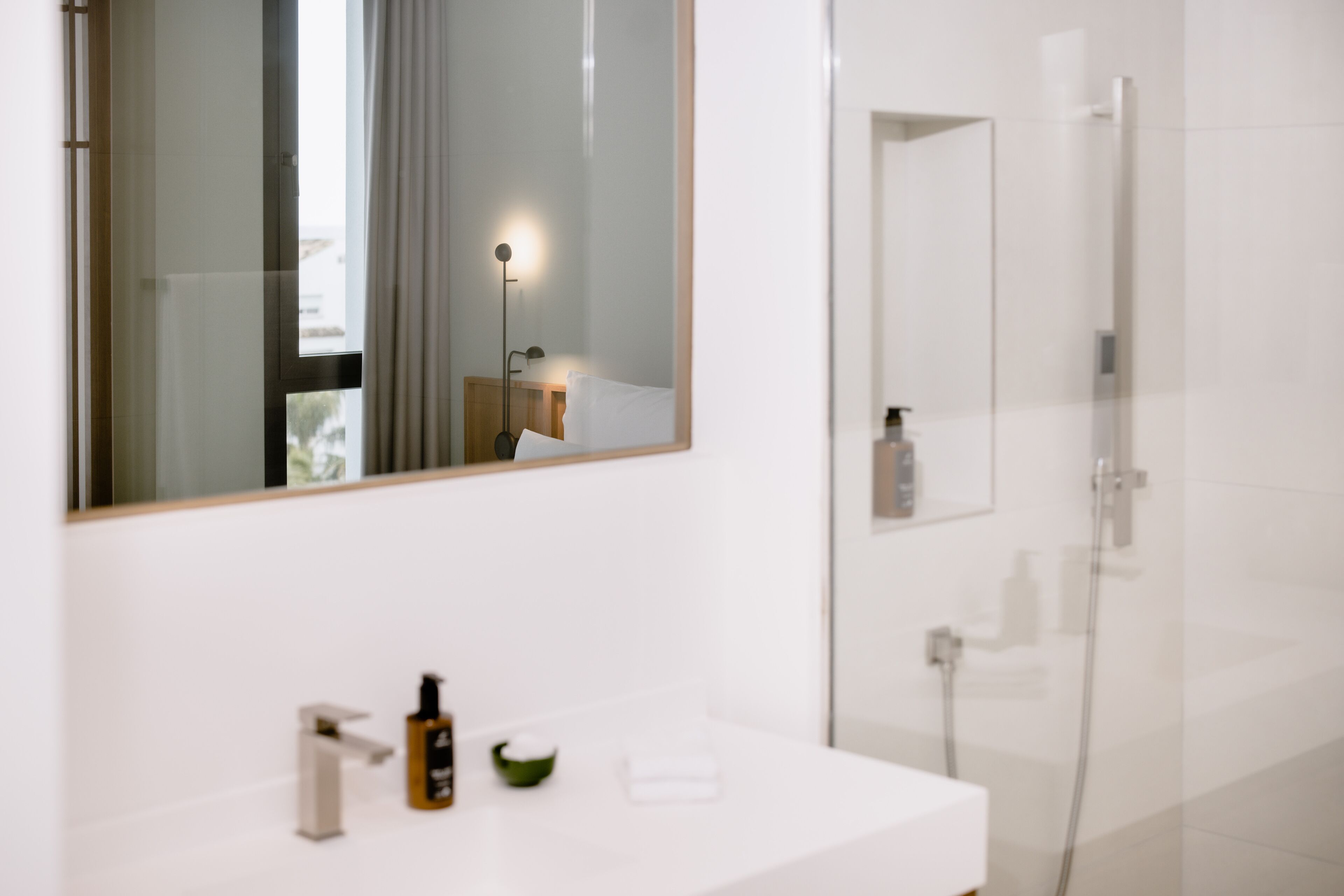 Een moderne badkamer met een wit wastafelmeubel, een spiegel en een douchecabine van glas.