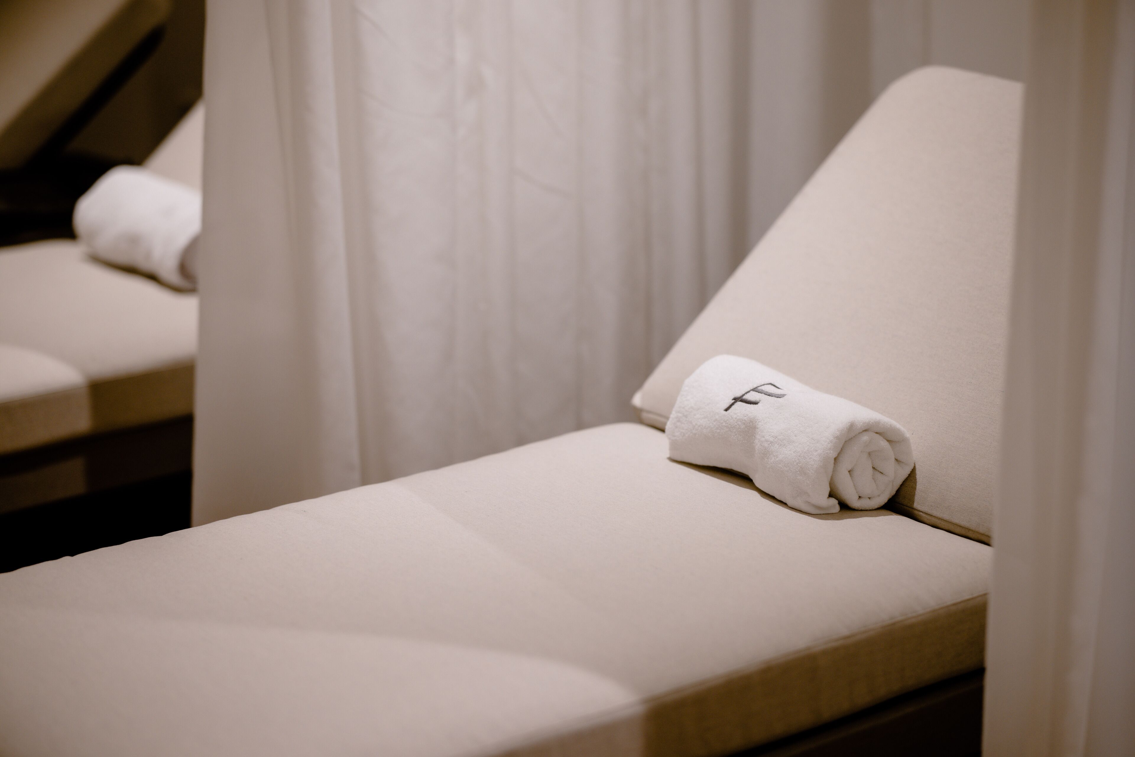Una habitación limpia y moderna con una cama individual, una toalla doblada con cuidado y una cortina.