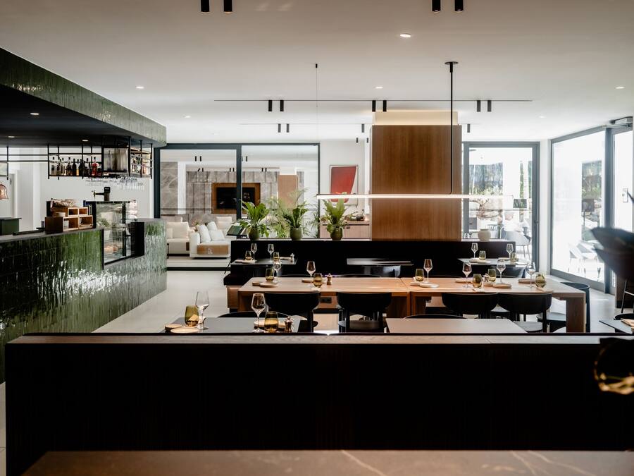 Un área de comedor moderna con una mesa larga, barra y ventanas amplias.