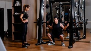 Ein Fitnessstudio mit einem Squat-Stand und einer Frau daneben.