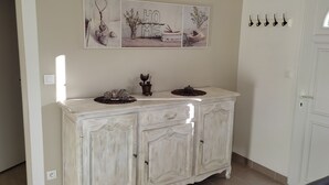 Un meuble blanc orné d’objets décoratifs, une œuvre d’art encadrée au-dessus, et une porte avec une fenêtre.