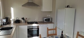 Una cocina compacta equipada con estufa a gas, microondas, horno y refrigerador.
