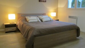 Un lit bien fait, avec une tête de lit, deux tables de chevet avec des lampes et une fenêtre avec des rideaux.