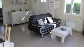 Un salon avec un canapé noir, une table basse blanche et un meuble blanc.