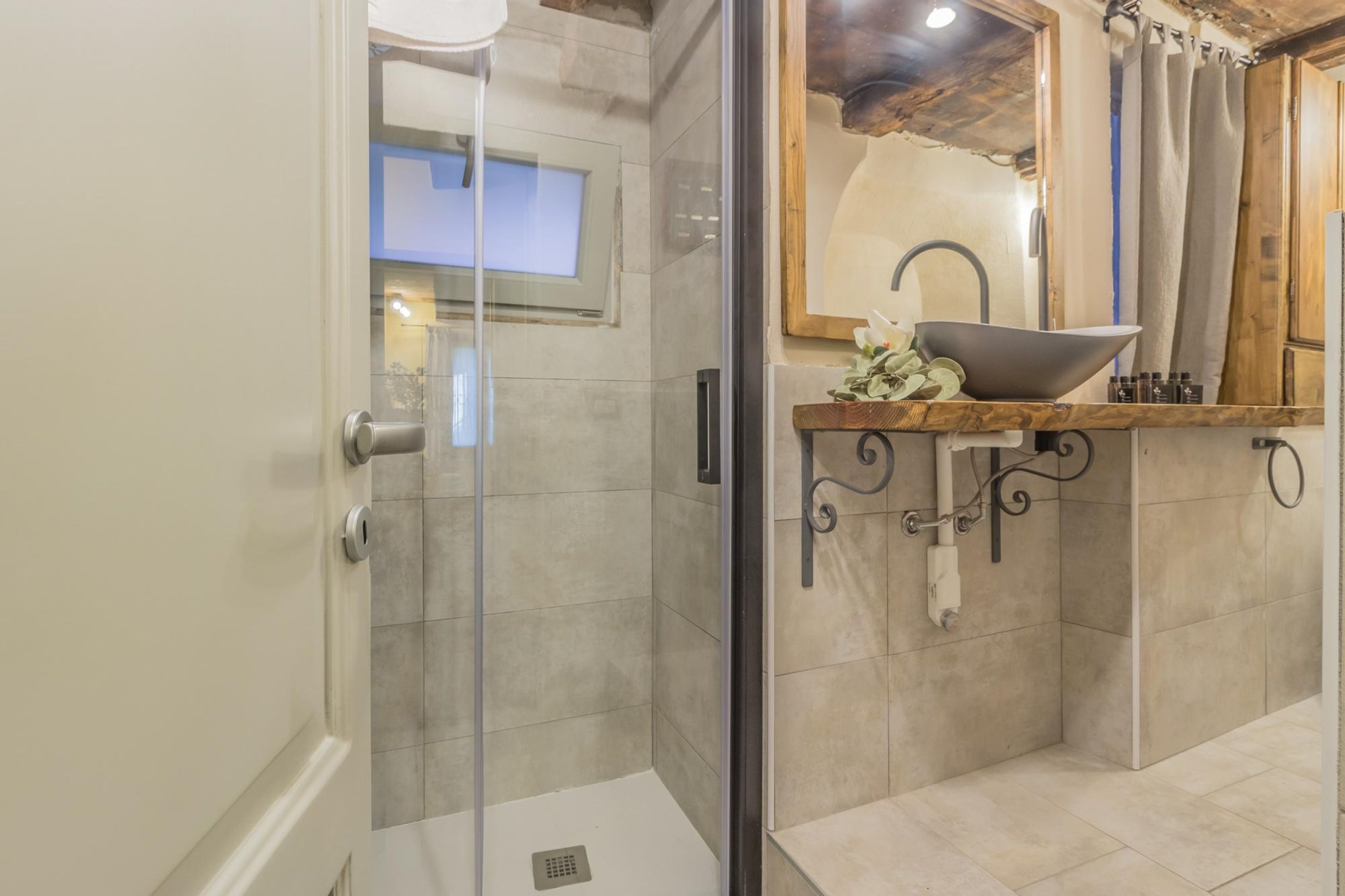 Ein modernes Badezimmer mit einer in Glas eingeschlossenen Dusche, einem Waschbecken mit dekorativer Schale und einem Holz-Waschtisch.