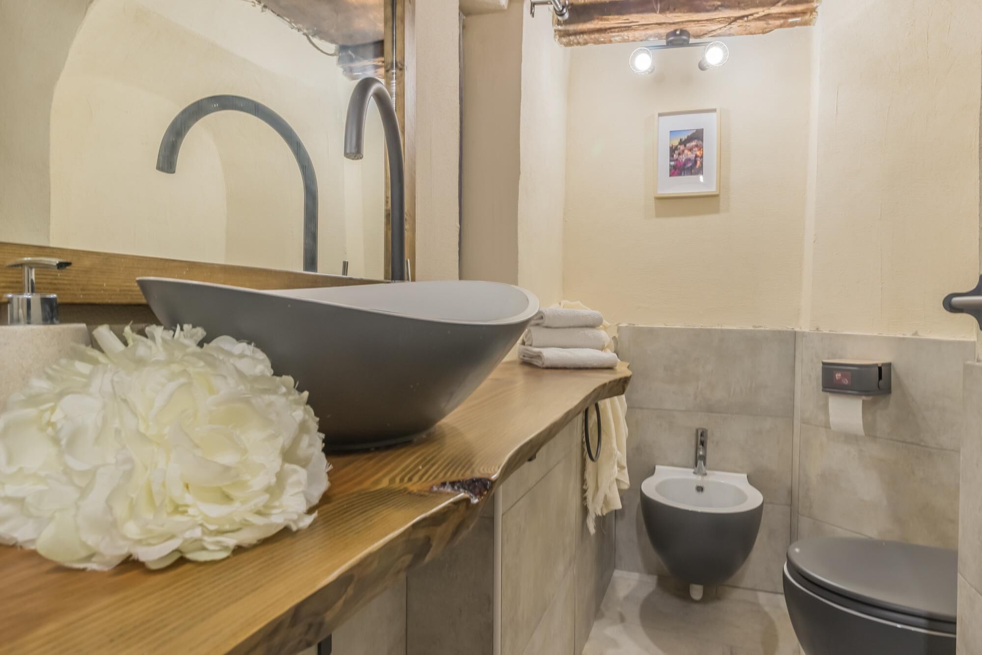 A modern bathroom with a large vessel sink, a bidet, and a toilet.