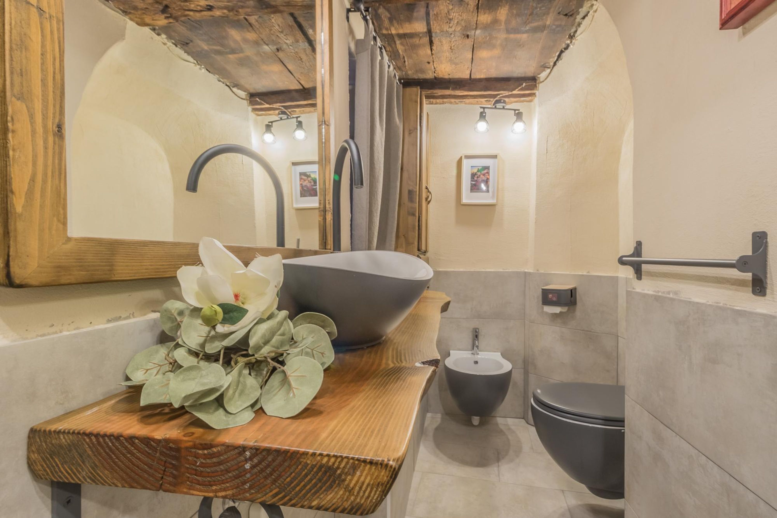 A modern bathroom with a wooden vanity, a large basin, a bidet, and a toilet.