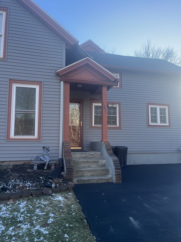 A two-story house with a front porch, a mailbox, and a number '161' on the door.