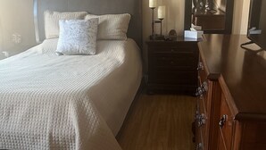 Une chambre à coucher comprenant un lit, des tables de chevet, une commode, un miroir et un panneau mural sur lequel est écrit « Détendez-vous ».