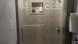 Une salle de bain moderne avec une douche à parois de verre, un meuble-lavabo et un miroir.