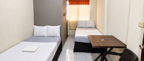 A hotel room with two beds, a small table, and a chair.