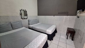 Una habitación pequeña y limpia, con dos camas, un espejo, una mesita y paredes de azulejos.