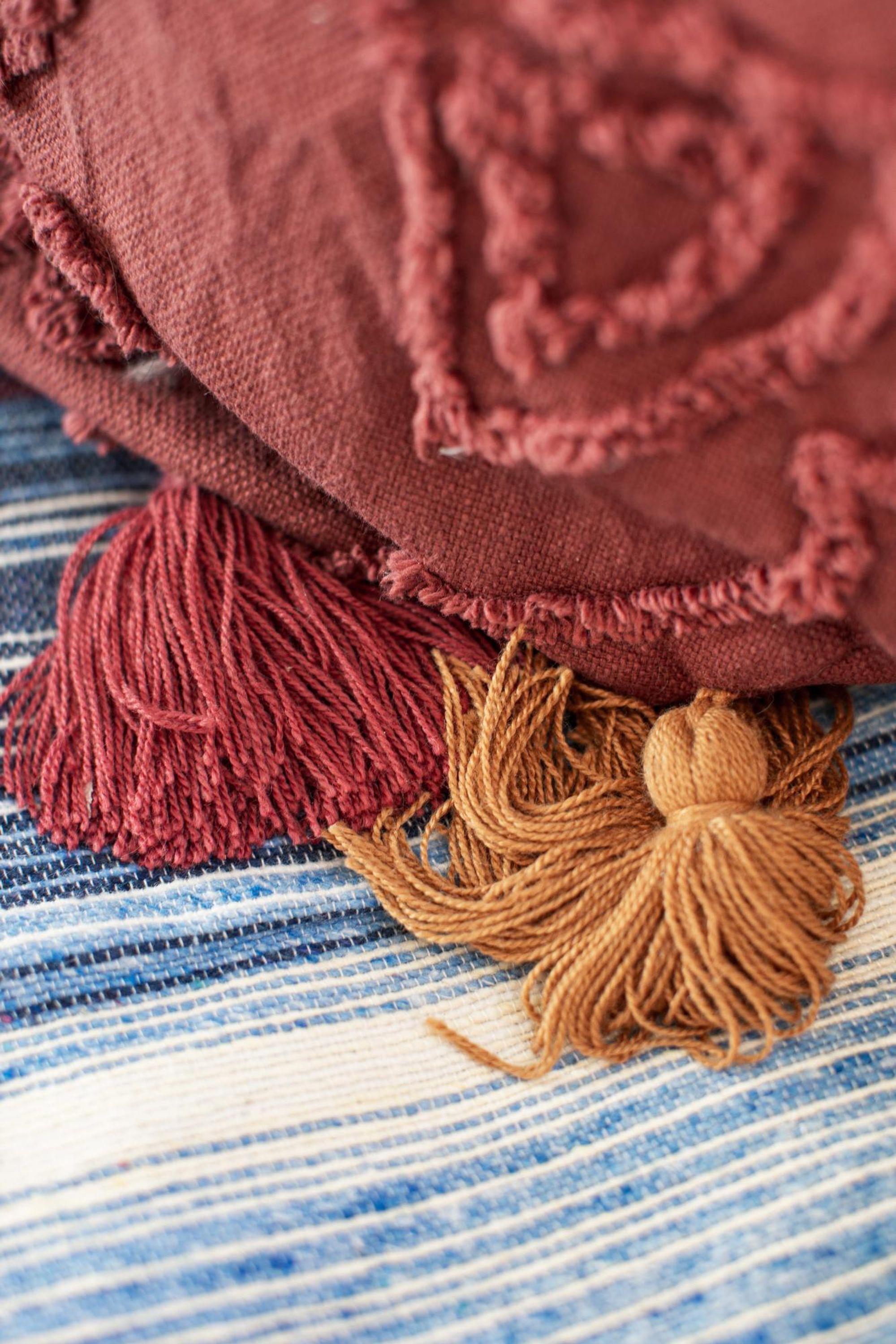 Close-up de um tecido texturizado com um franjado e um pompom pequeno.