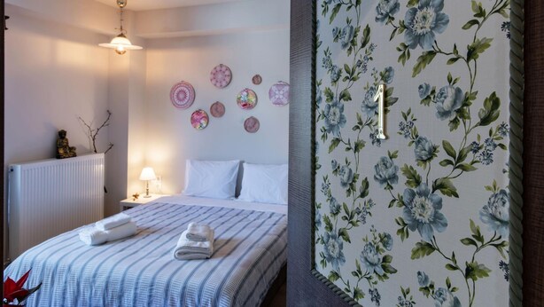 A hotel room with a bed, a radiator, a wall with circular decorations, and a floral wallpaper. - Stagiates Guest House Room 1 (Volos)