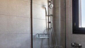 A modern bathroom with a glass-enclosed shower, a toilet, and patterned tiles. - Stagiates Guest House Room 1 (Volos)