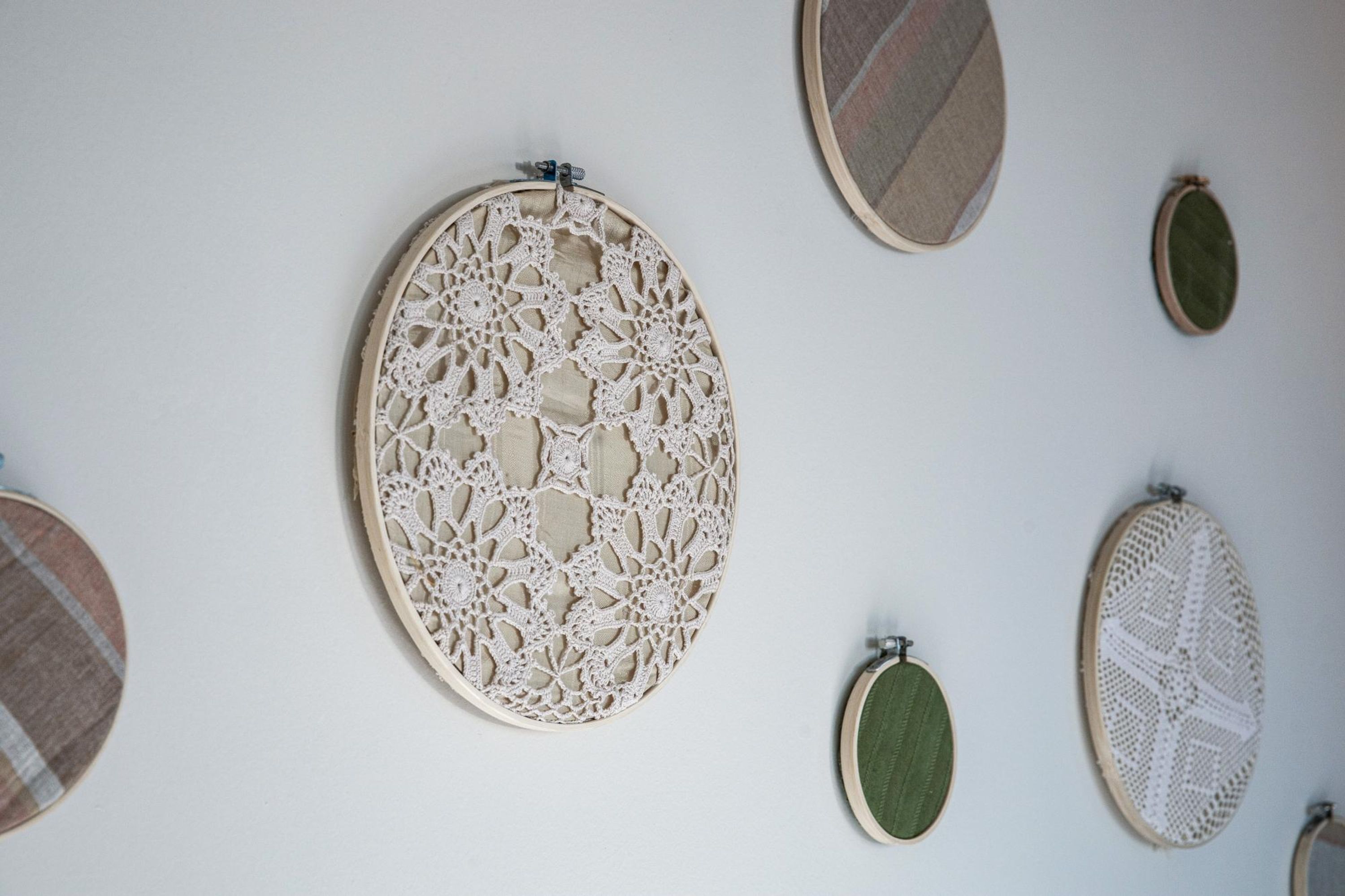 Uma parede com vários aros de bordado de diferentes tamanhos e estampas.