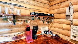 A cozy cabin interior with wooden walls, a coffee station, mugs, and a sign with rules. - Music Mountain Retreat Cabin B (Hot Springs)