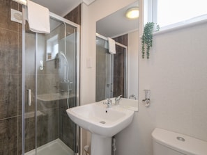 Ein modernes Badezimmer mit Duschkabine aus Glas, einem weißen Waschbecken und einer Toilette.