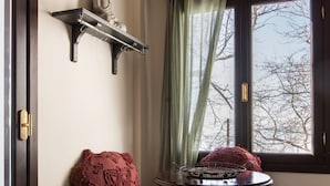 A room with a bench, a small table, a Buddha statue, and a window with curtains. - Stagiates Guest House Room 2 (Volos)