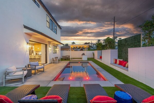 Une maison moderne dotée d’une piscine, d’un espace salon extérieur et d’une pelouse bien entretenue.