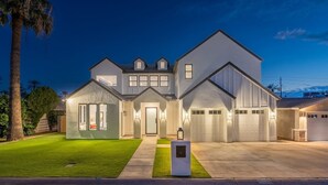 A modern two-story house with a well-maintained lawn, a driveway, and a garage. - Desert Escape | Poolside BBQs, Sunset Views & Spacious Comfort (Phoenix)