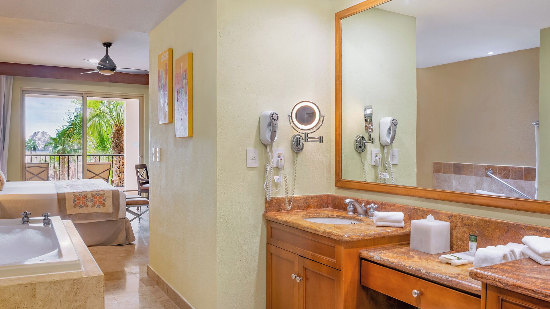 A hotel bathroom with a bathtub, two sinks, a vanity, and a large mirror.