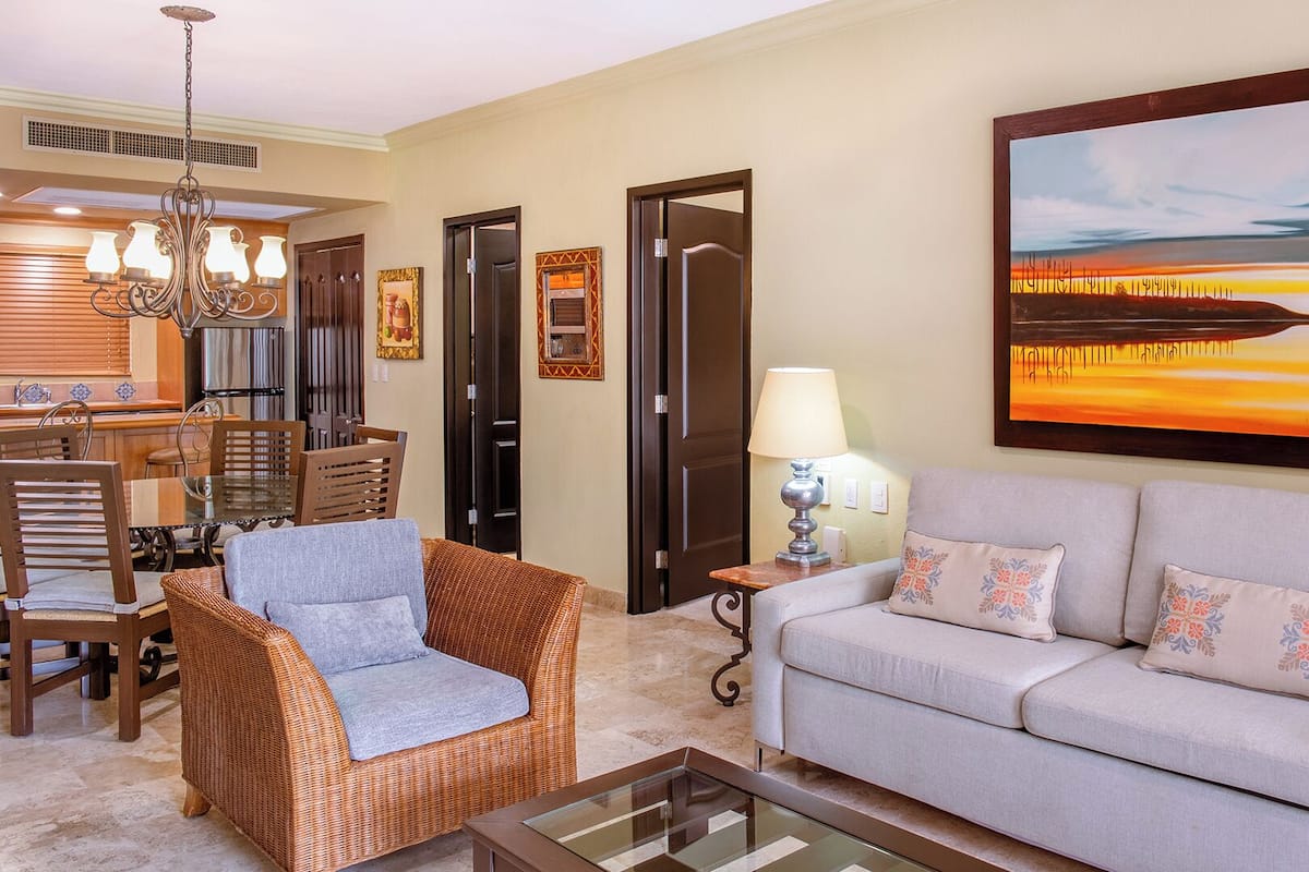 A living room with a sofa, two chairs, a coffee table, a lamp, and a painting on the wall.