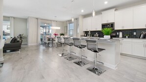 A modern kitchen with white cabinets, stainless steel appliances, and a central island with bar stools.
