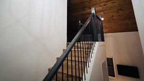 Een trap met een houten leuning en een moderne kroonluchter.