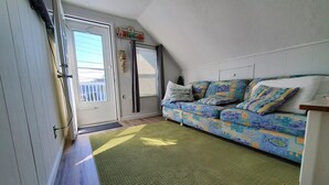 A room with a sofa, a door, and a window.