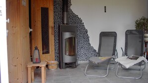 Una habitación con chimenea de piedra, puerta de madera y dos sillas de metal.
