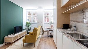 A modern kitchen with a sink, countertop, and a dining area with a table and chairs. - Urban House - A - by LovelyStay (Porto)