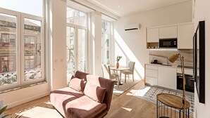 Un appartement moderne comprenant un canapé, une table à manger et un coin cuisine.