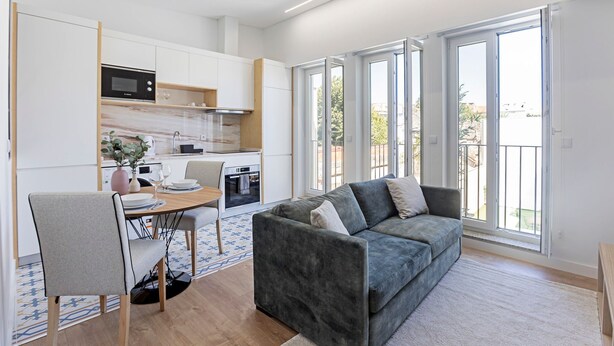 Un apartamento moderno con cocina, comedor y sala de estar con sofá gris.