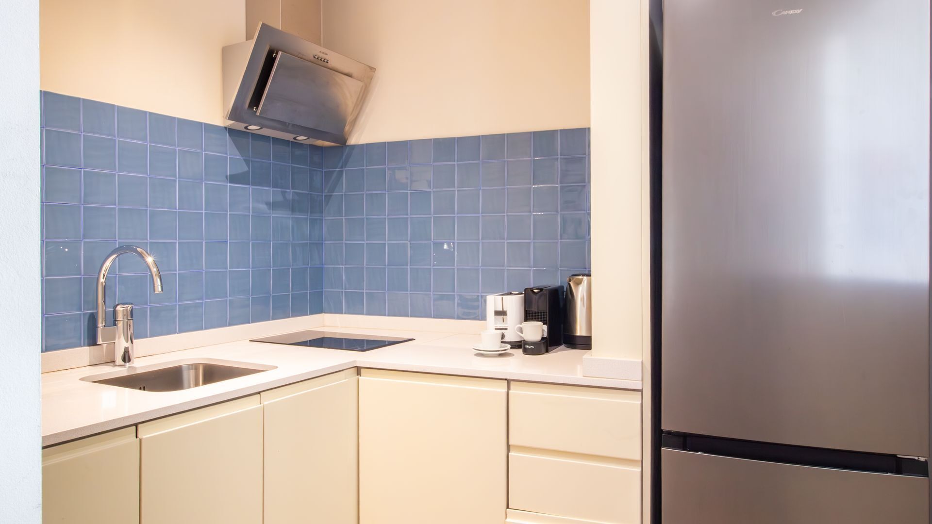 A kitchen with two sinks, a coffee maker, and a refrigerator.